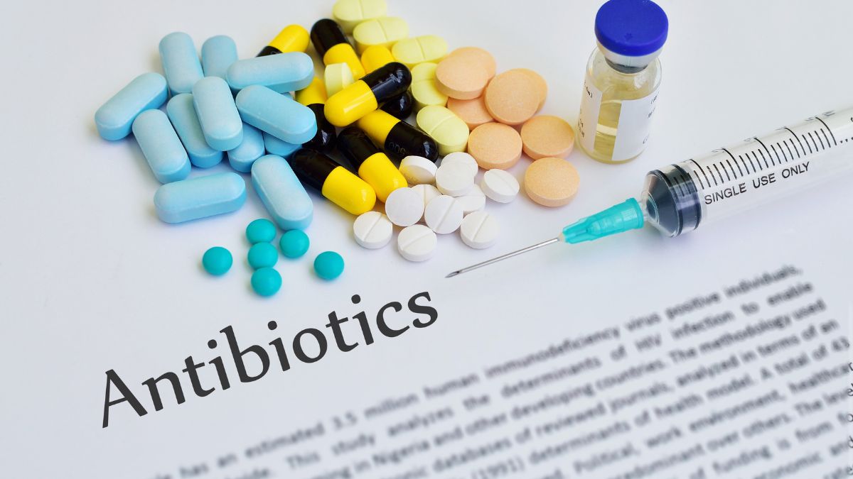 Rôzne typy antibiotík a injekčná striekačka na papieri s textom o antibiotikách.