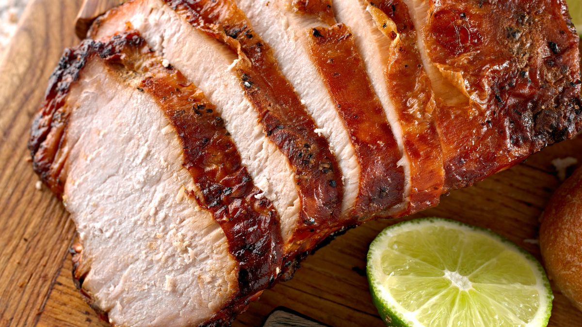 Plátky šťavnatého bravčového mäsa na drevenej doske s limetkou.