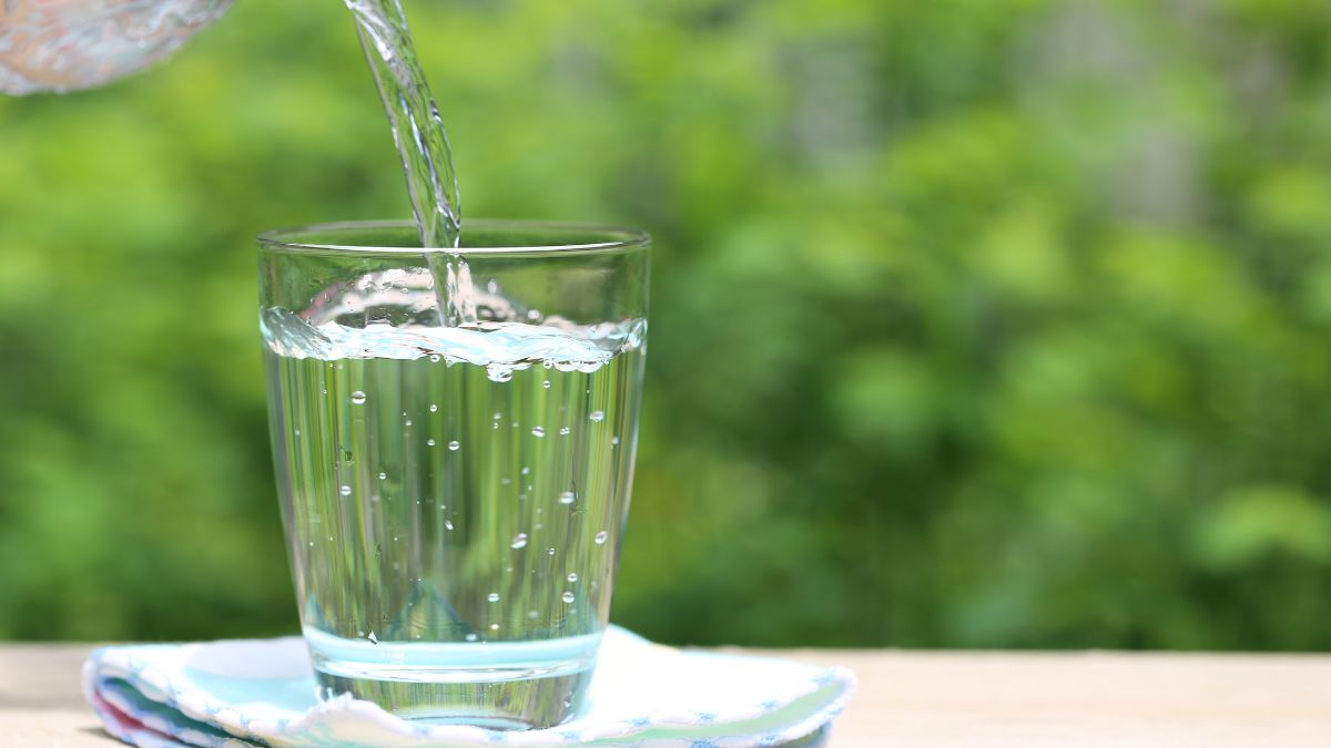 Sklenený pohár s destilovanou vodou, do ktorého sa práve nalieva voda.