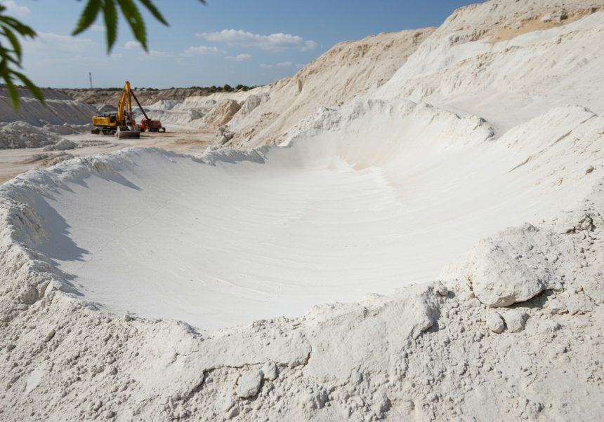 Biely kaolín v lome, s ťažobným zariadením v pozadí.