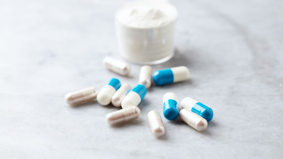 Rôzne kapsuly a prášok na stole, symbolizujúce doplnky stravy na chudnutie.