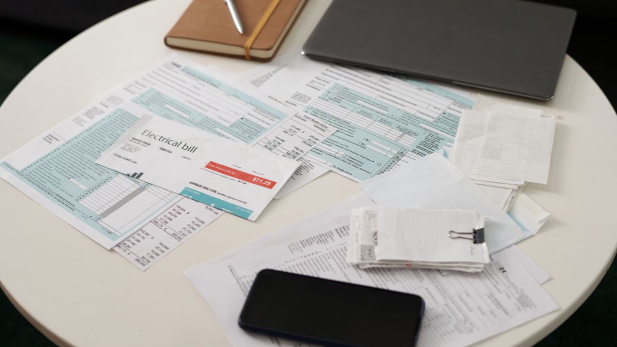 Stôl s rôznymi účtami a dokumentmi, vrátane elektrického účtu.