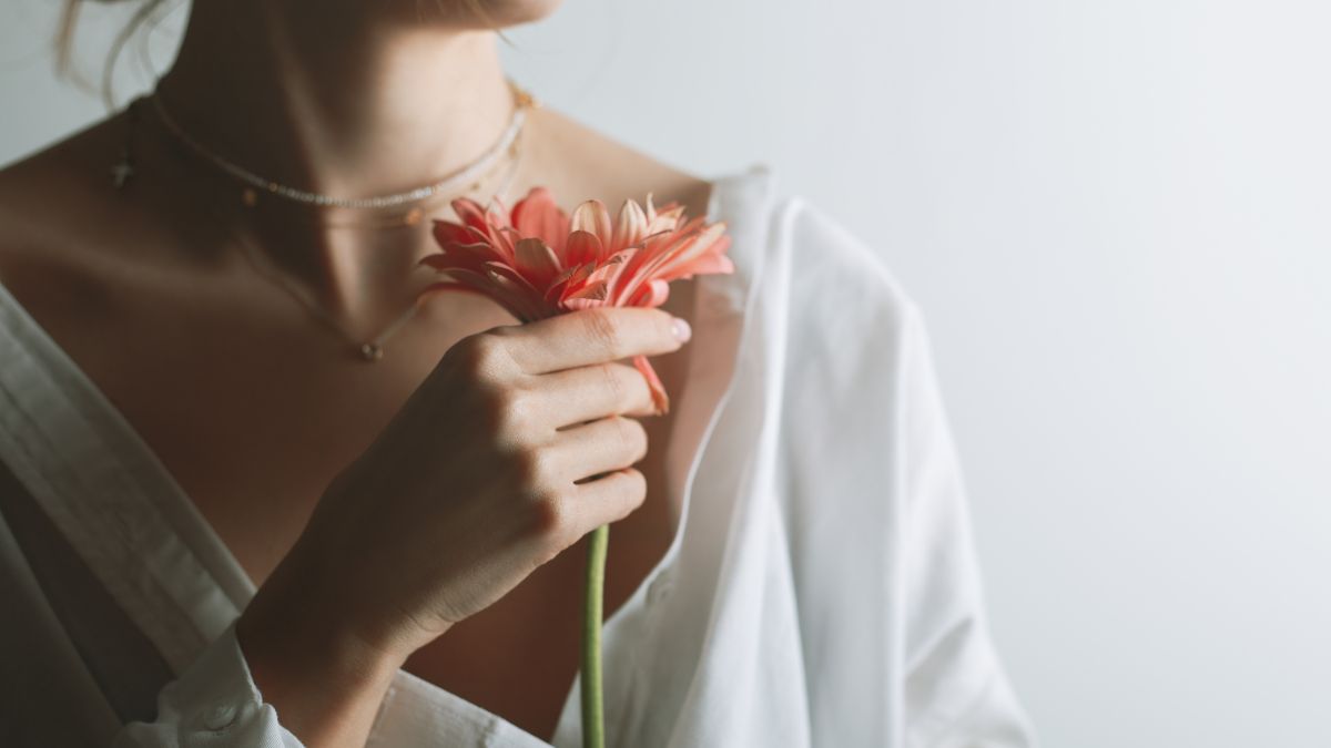 Žena v bielom tričku drží červený kvet, symbolizujúci ženskosť a zdravie.