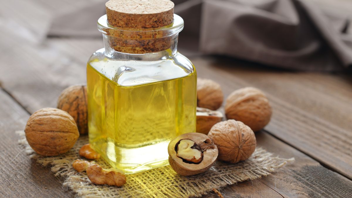 Fľaša orechového oleja s orechmi na drevenej doske.