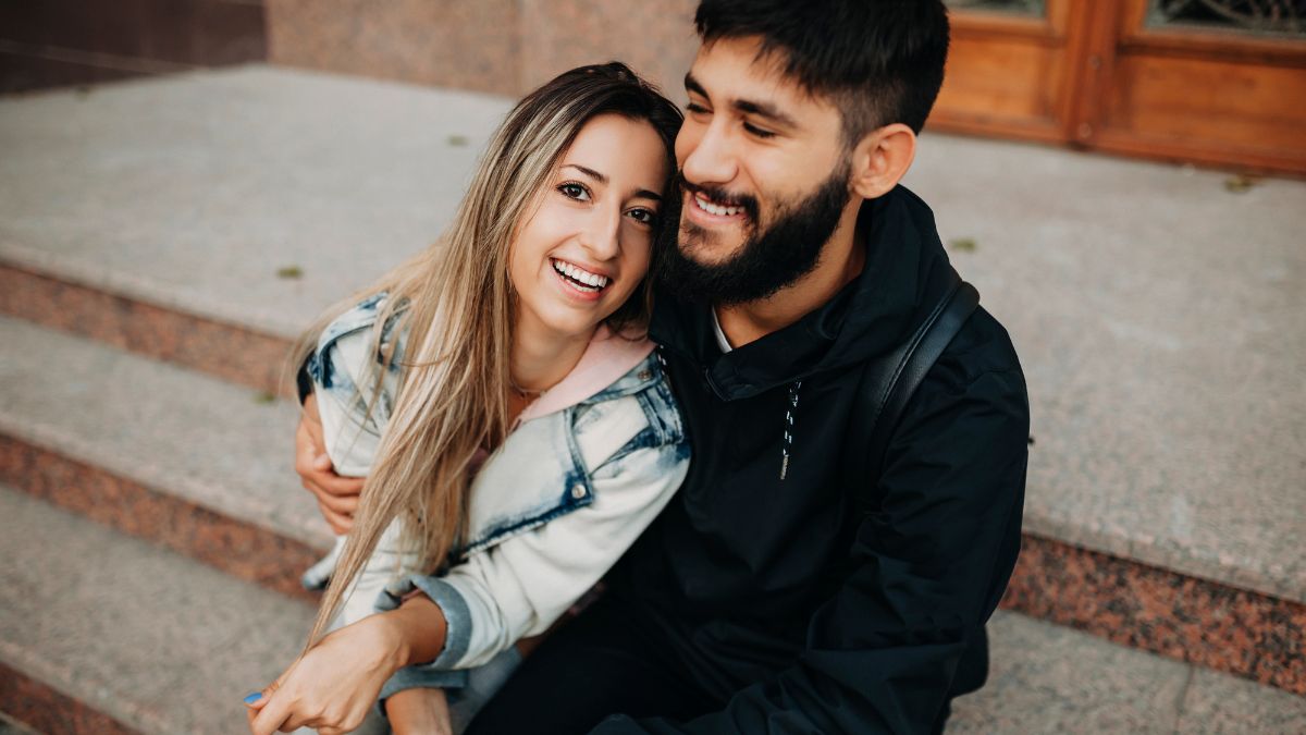 Dvojica šťastných mladých ľudí sa objíma a usmieva sa na schodoch.