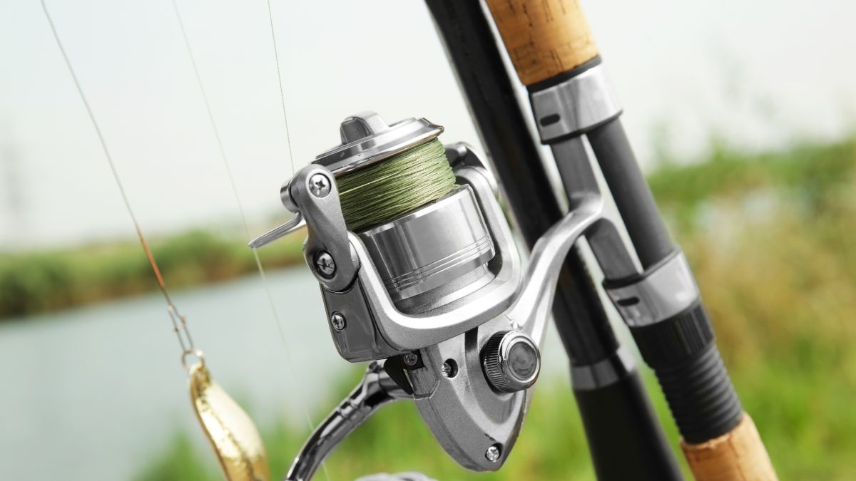 Detail rybárskeho navijaka s jemne navinutým vlascem na pozadí vodnej plochy.