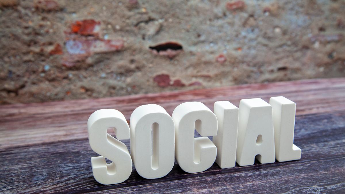 Biele písmená tvoriace slovo 'SOCIAL' na drevenom stole.