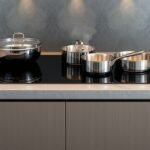 Indukčná varná doska s hrncami a panvicou v moderných kuchynských interiéroch