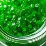 Zelené gélové kapsule chlorelly v sklenenom obale.