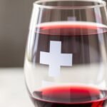 Sklenený pohár s červeným vínom a symbolom kríža.