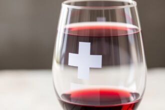 Sklenený pohár s červeným vínom a symbolom kríža.