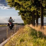 Motocykel na ceste medzi stromami pri západe slnka v Európe